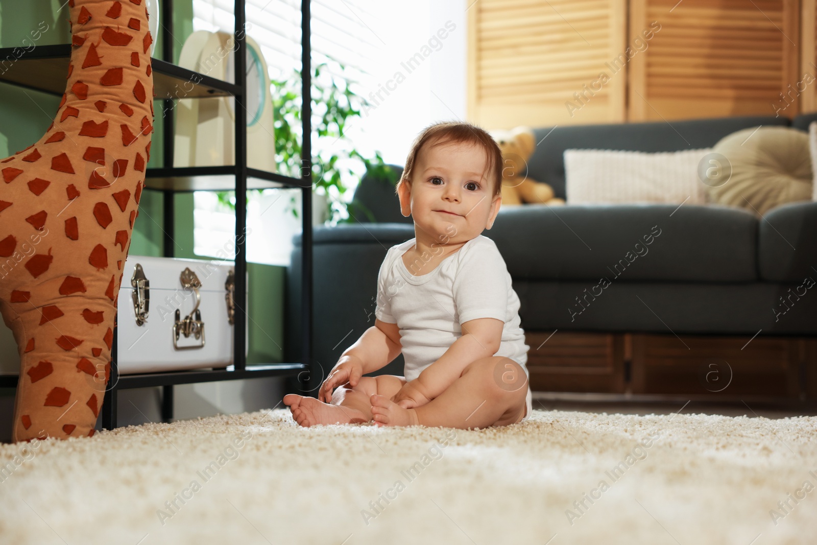 Cute little baby sitting on carpet at home Photo of Cute little baby sitting on carpet at home