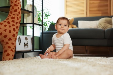 Photo of Cute little baby sitting on carpet at home