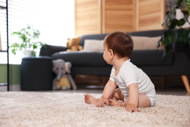 Photo of Cute little baby sitting on carpet at home, space for text