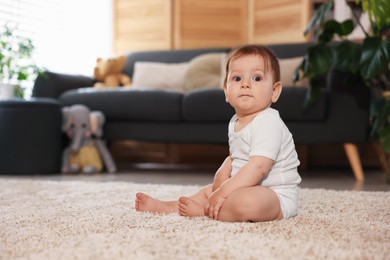 Photo of Cute little baby sitting on carpet at home, space for text