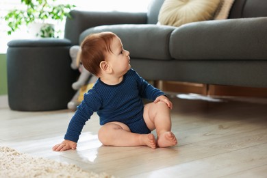Photo of Cute little baby sitting on floor at home