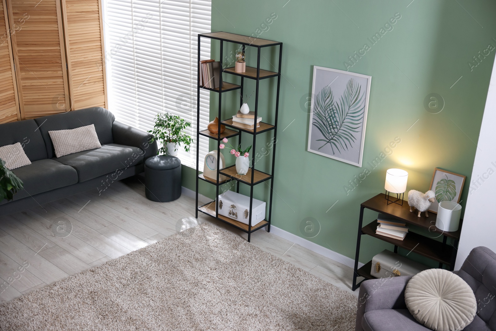 Comfortable sofa, shelving unit, armchair and decor in living room. Interior design Photo of Comfortable sofa, shelving unit, armchair and decor in living room. Interior design