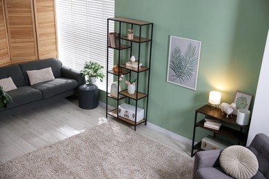 Photo of Comfortable sofa, shelving unit, armchair and decor in living room. Interior design