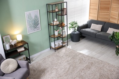 Photo of Comfortable sofa, shelving unit, armchair and decor in living room. Interior design