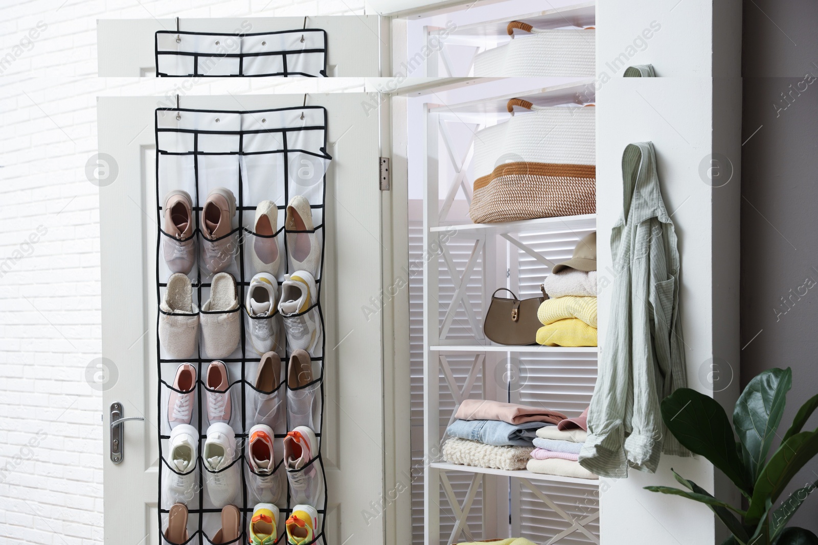 Organizer with different footwear on door and clothes indoors. Shoe storage Photo of Organizer with different footwear on door and clothes indoors. Shoe storage