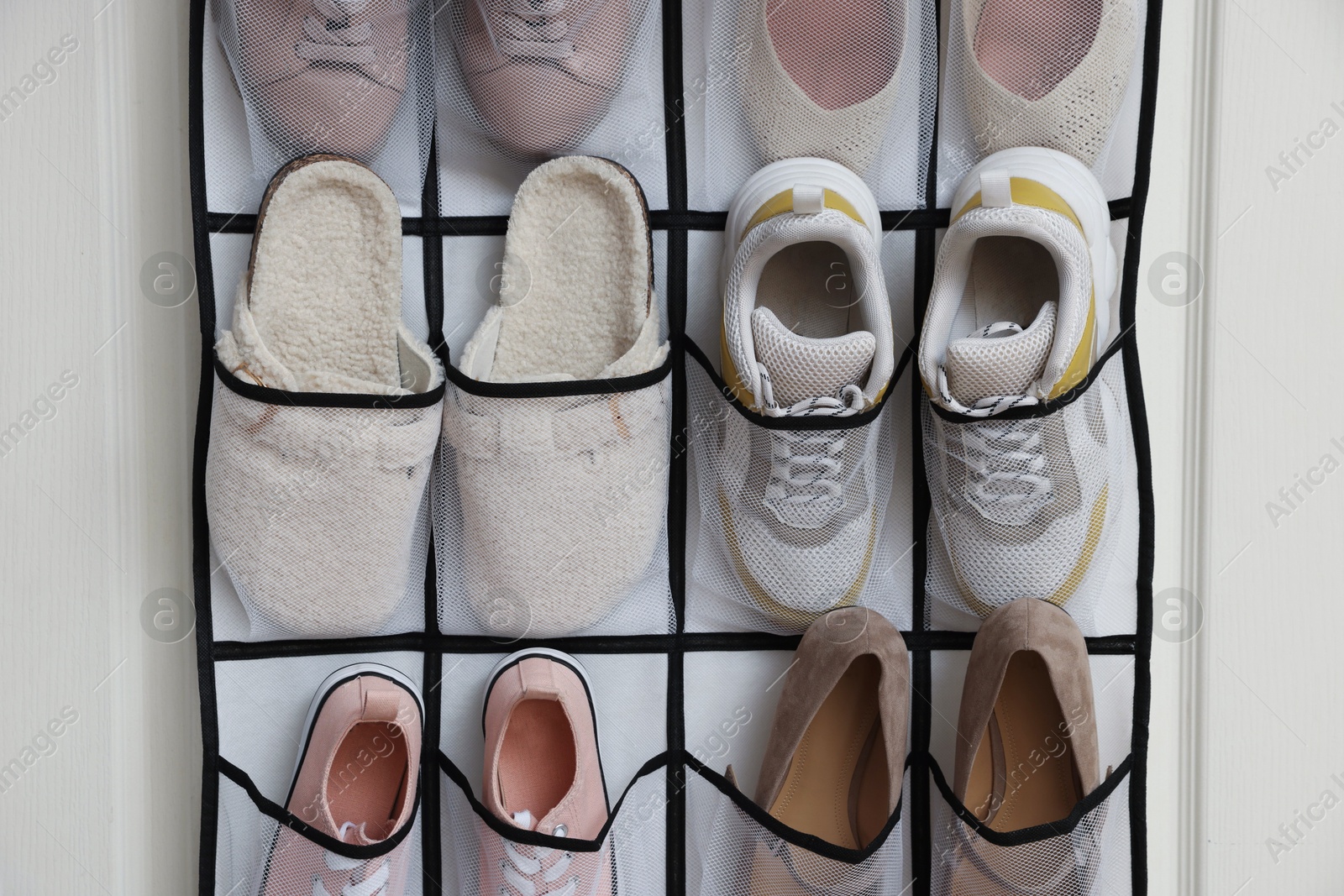 Organizer with different footwear on door indoors. Shoe storage Photo of Organizer with different footwear on door indoors. Shoe storage