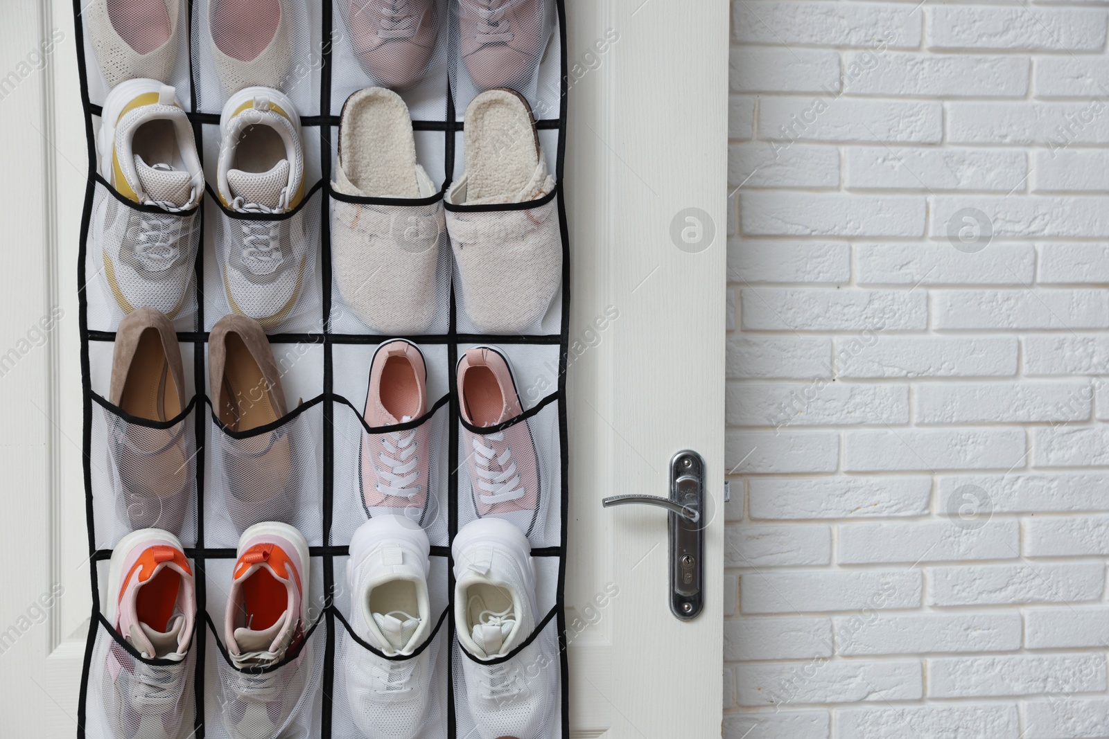 Organizer with different footwear on door indoors, space for text. Shoe storage Photo of Organizer with different footwear on door indoors, space for text. Shoe storage