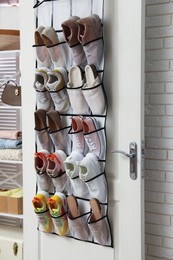 Photo of Organizer with different footwear on door indoors. Shoe storage