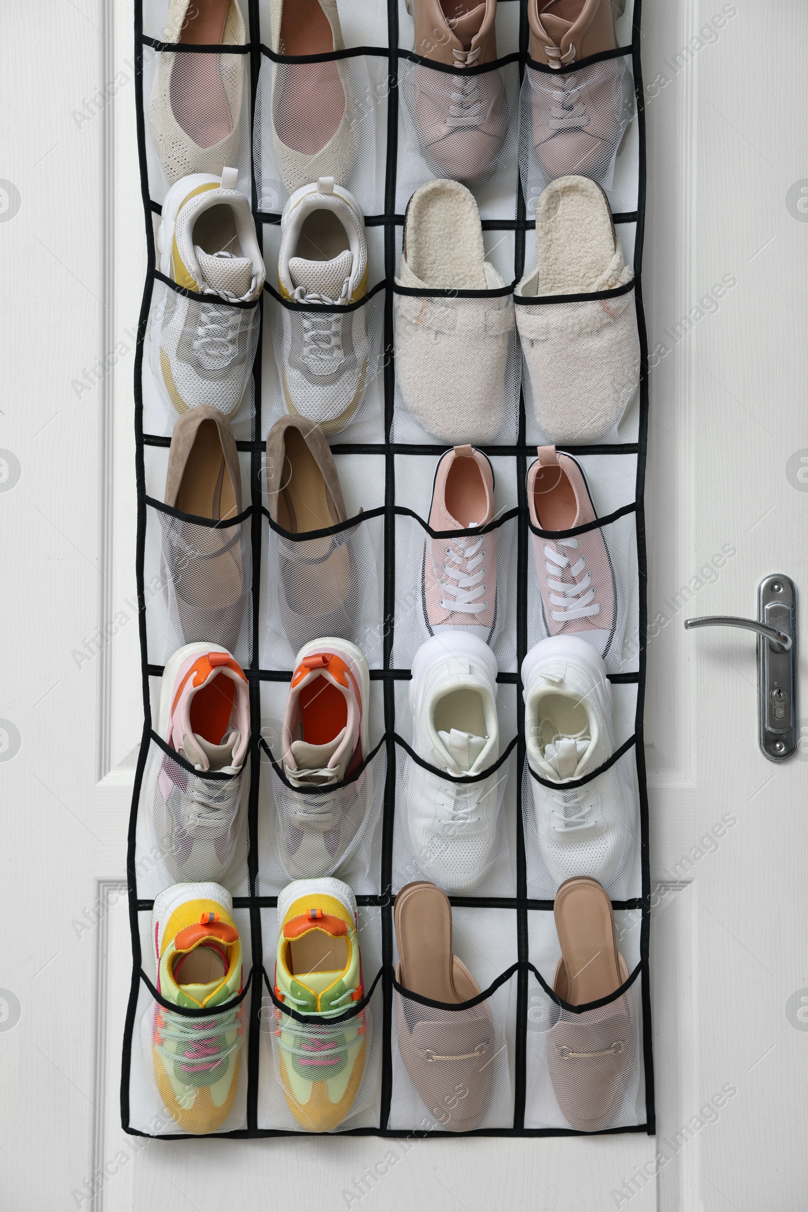 Organizer with different footwear on door indoors. Shoe storage Photo of Organizer with different footwear on door indoors. Shoe storage