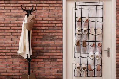 Photo of Organizer with different footwear on door and clothes indoors