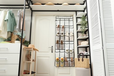 Photo of Organizer with different footwear, accessories and clothes indoors, low angle view. Shoe storage