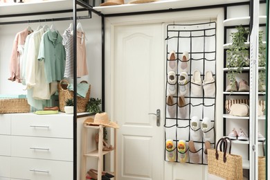 Photo of Organizer with different footwear, accessories and clothes indoors. Shoe storage