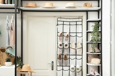 Photo of Organizer with different footwear, accessories and clothes indoors. Shoe storage