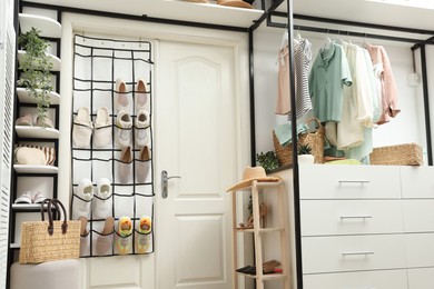 Photo of Organizer with different footwear, accessories and clothes indoors. Shoe storage