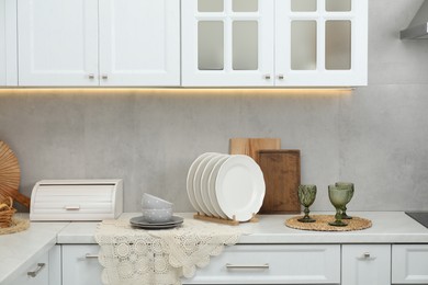 Photo of Clean dishware and glasses on countertop in kitchen