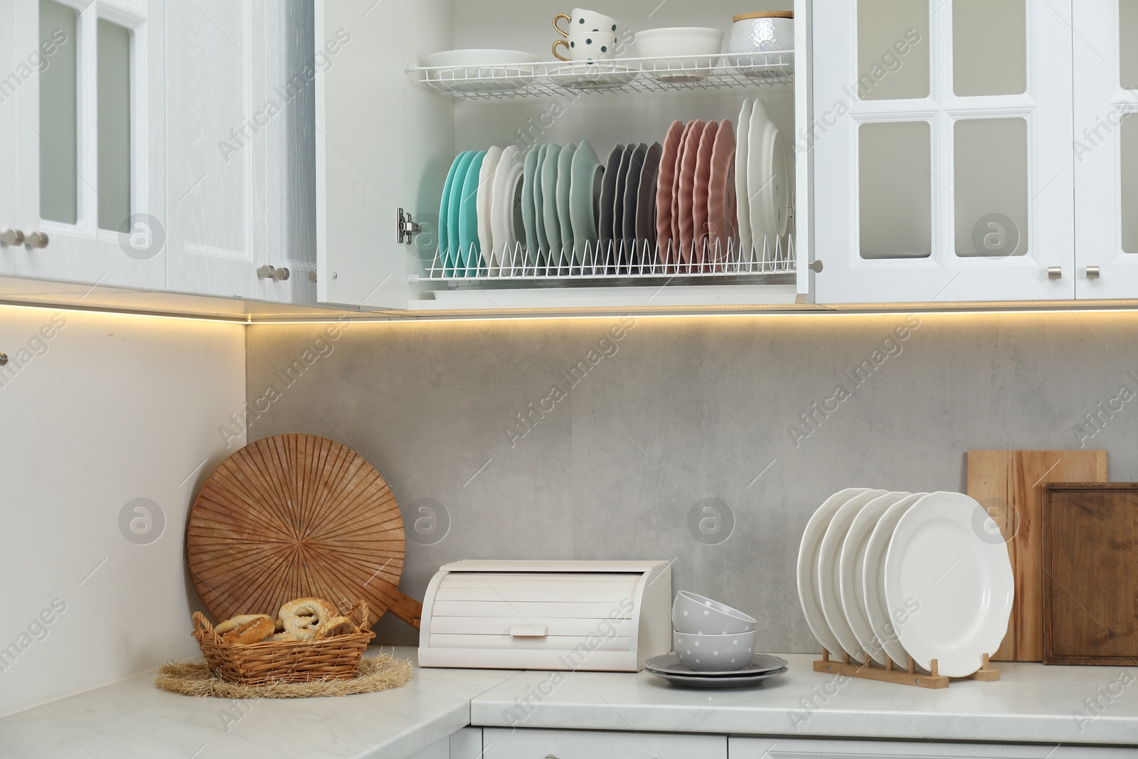 Photo of Clean dishware and cups on shelves in cabinet indoors
