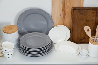 Photo of Clean dishware and cups on shelf in cabinet indoors