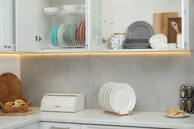 Photo of Clean dishware and cups on shelves in cabinets indoors