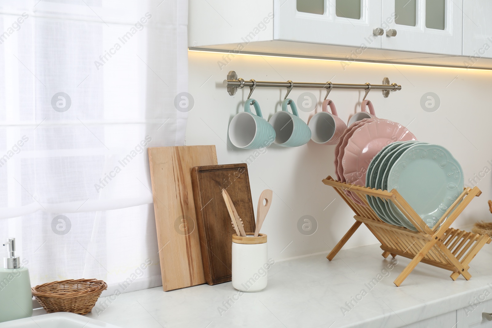 Photo of Drying rack with plates, cups and other utensils in kitchen