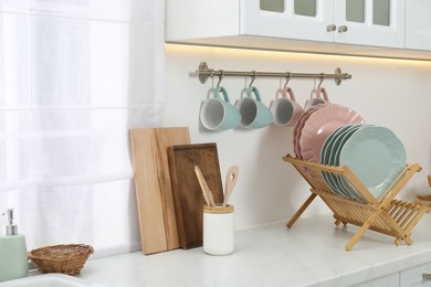 Photo of Drying rack with plates, cups and other utensils in kitchen