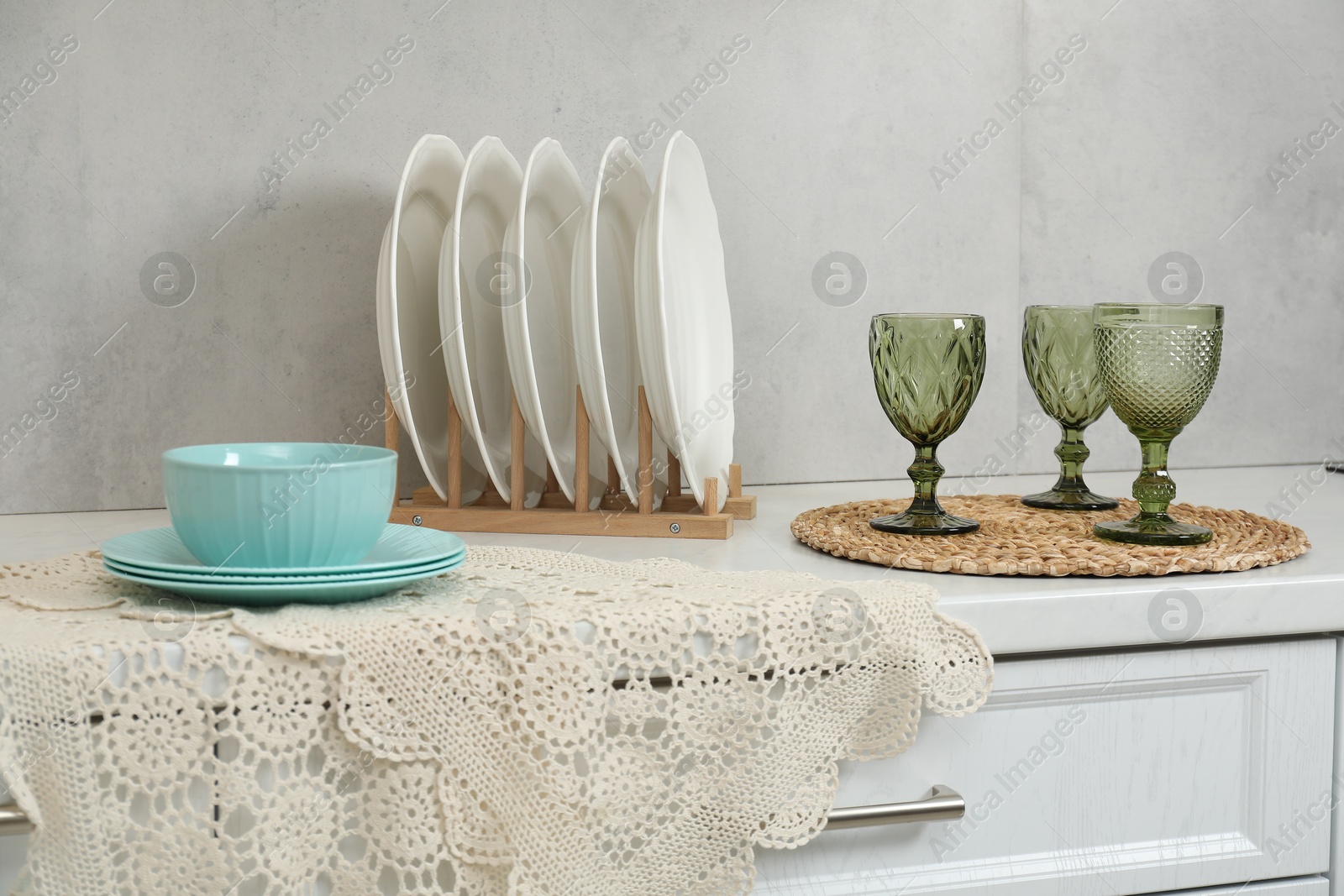 Photo of Drying rack with plates, bowl and glasses on countertop in kitchen