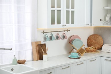 Photo of Clean dishware, cups and other kitchen utensils on countertop indoors