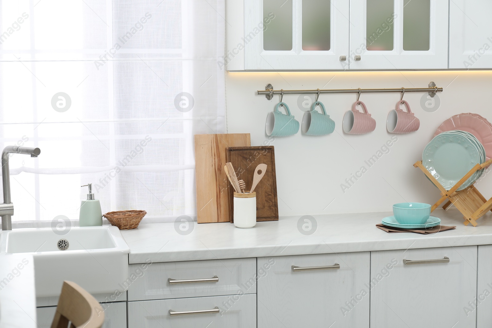 Photo of Different dishware on countertop and cups in kitchen