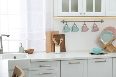 Photo of Different dishware on countertop and cups in kitchen