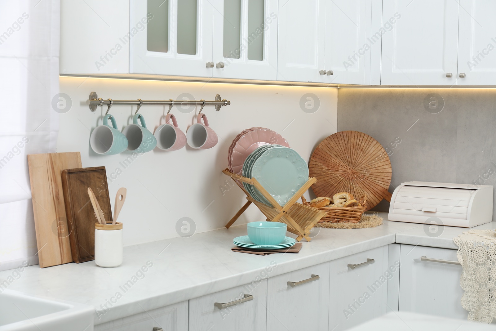 Photo of Different dishware on countertop and cups in kitchen