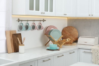 Photo of Different dishware on countertop and cups in kitchen