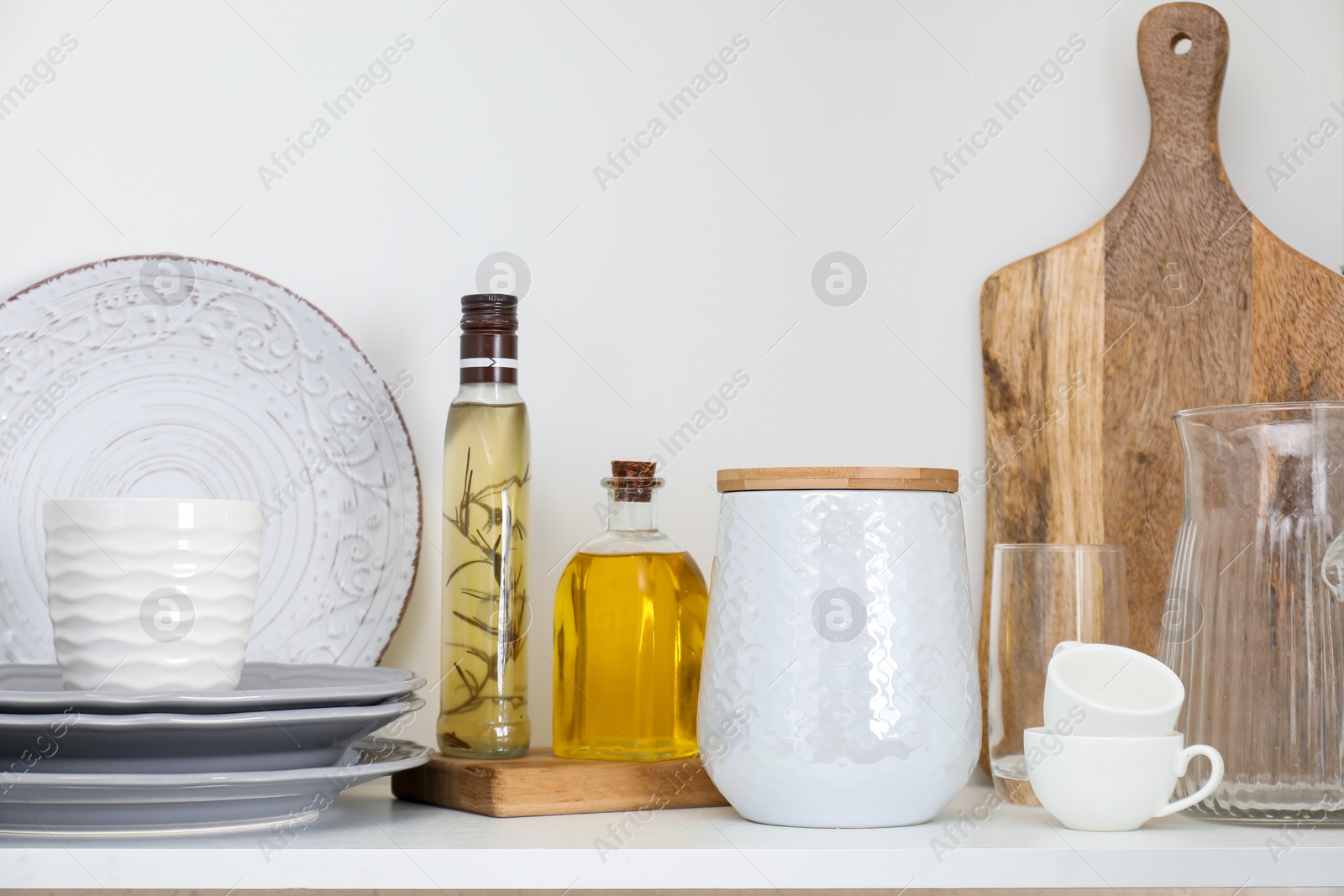 Photo of Clean dishware, cups and spices on shelf in cabinet indoors