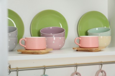 Photo of Different dishware and cups on shelf in cabinet indoors, closeup