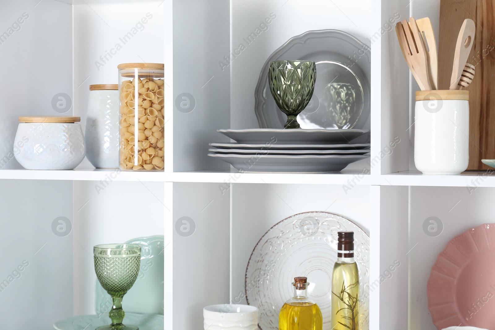 Photo of Shelving unit with different dishware, glasses and other kitchen utensils indoors