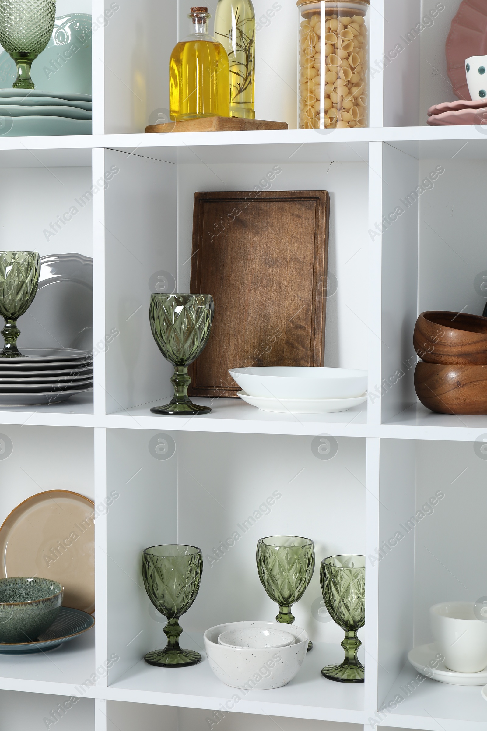 Photo of Shelving unit with different dishware, glasses and other kitchen utensils indoors