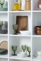 Photo of Shelving unit with different dishware, glasses and other kitchen utensils indoors