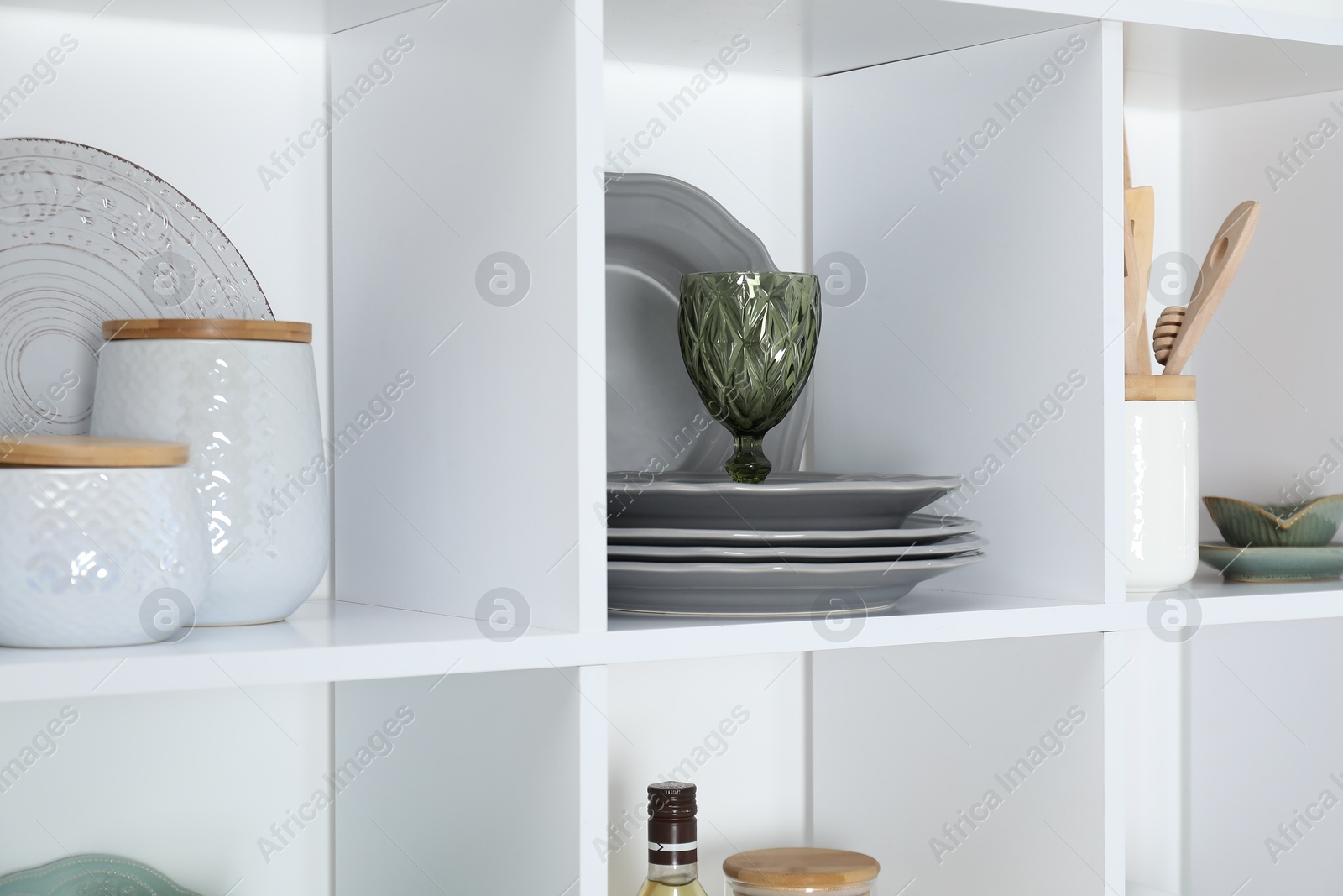 Photo of Shelving unit with different dishware, glass and other kitchen utensils indoors