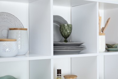 Photo of Shelving unit with different dishware, glass and other kitchen utensils indoors