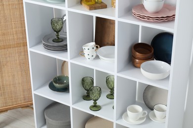 Photo of Shelving unit with different dishware, glasses and cups indoors