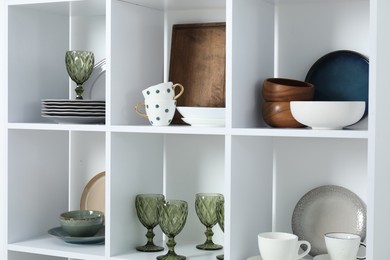 Photo of Shelving unit with different dishware, glasses and cups indoors