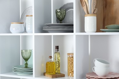 Photo of Shelving unit with different dishware, glasses and other kitchen utensils indoors