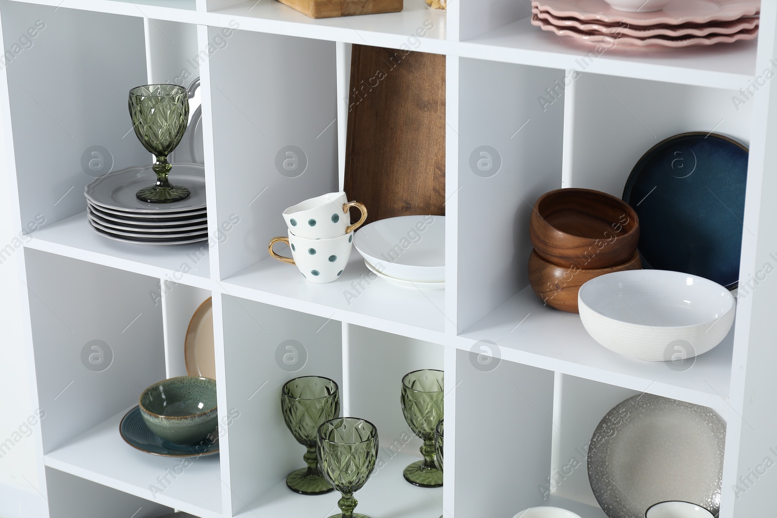Photo of Shelving unit with different dishware, glasses and cups indoors