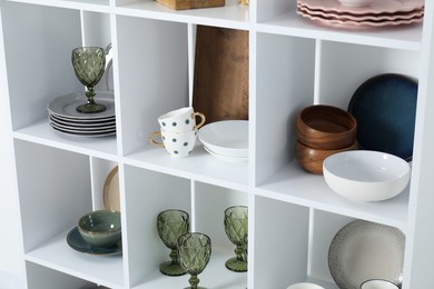 Photo of Shelving unit with different dishware, glasses and cups indoors