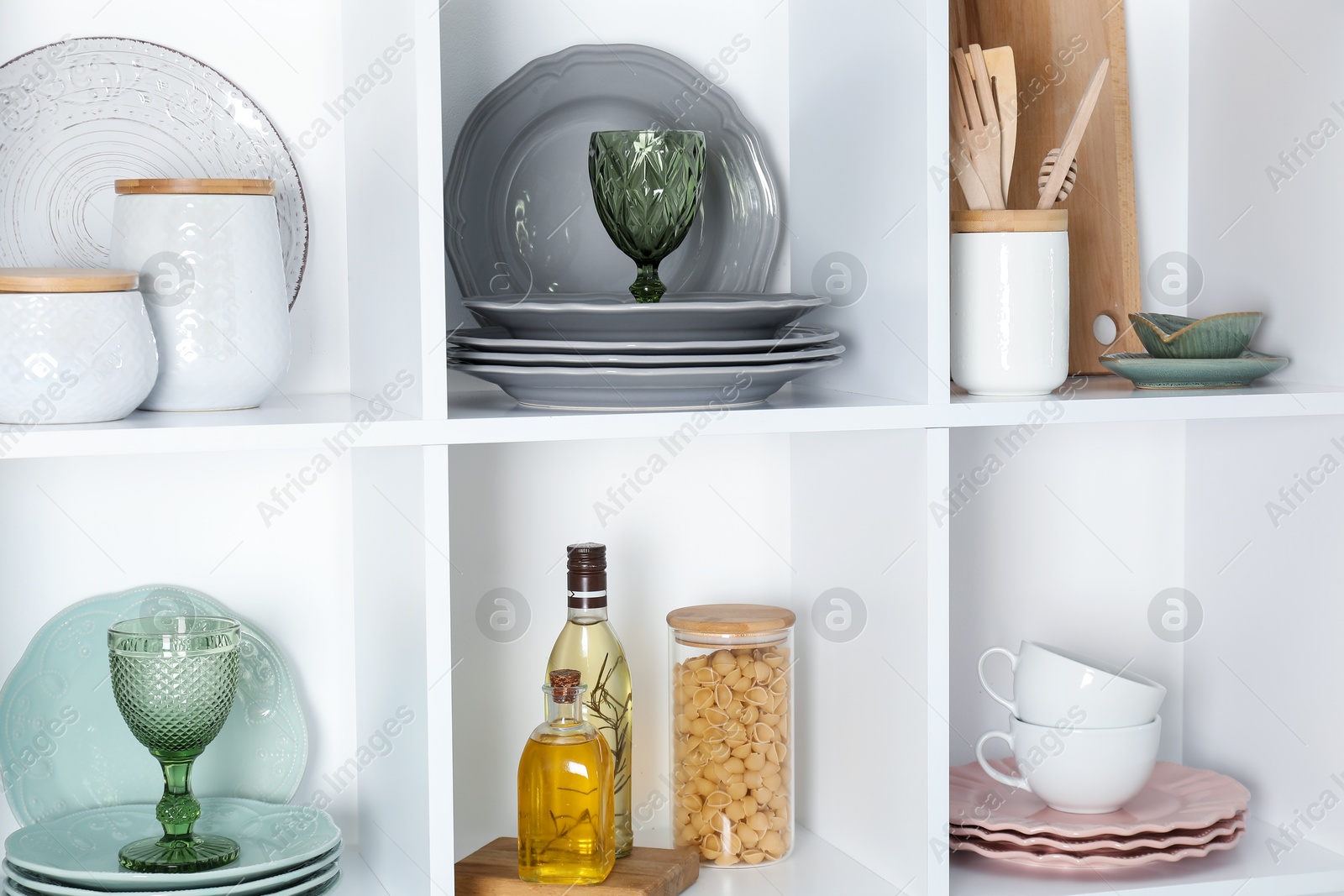 Photo of Shelving unit with different dishware, glasses and other kitchen utensils indoors