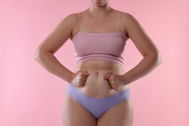 Photo of Liposuction. Woman in underwear touching her belly on pink background, closeup