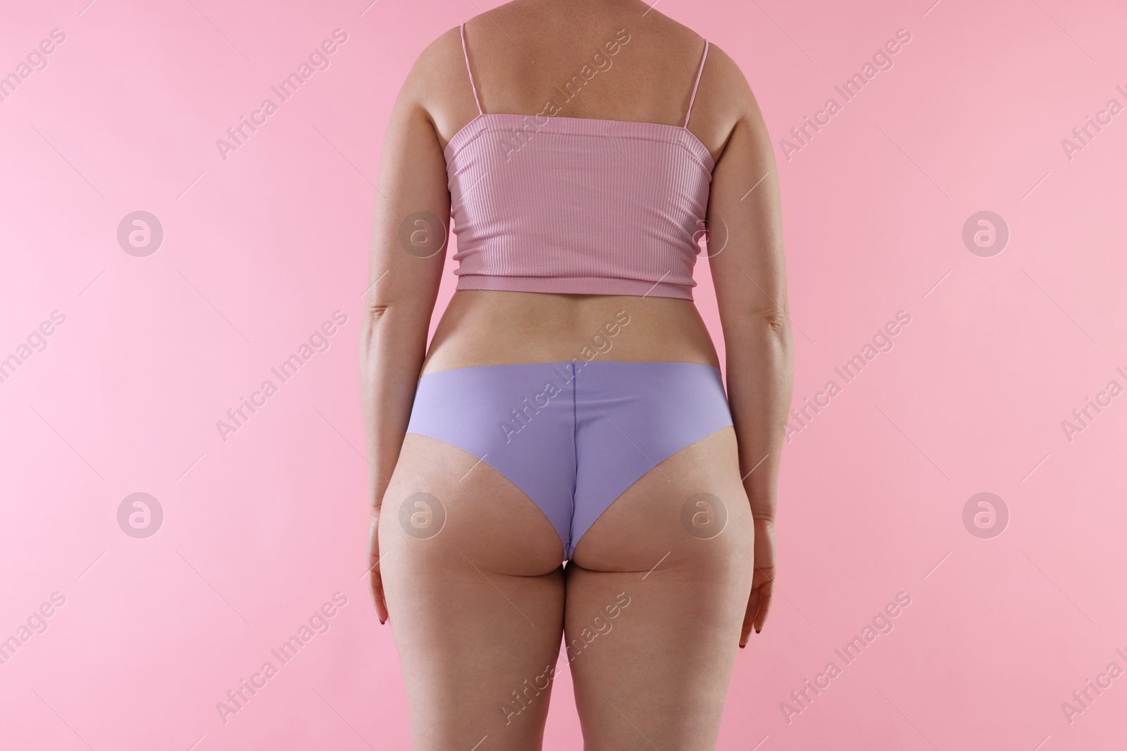 Liposuction. Woman in underwear on pink background, back view Photo of Liposuction. Woman in underwear on pink background, back view