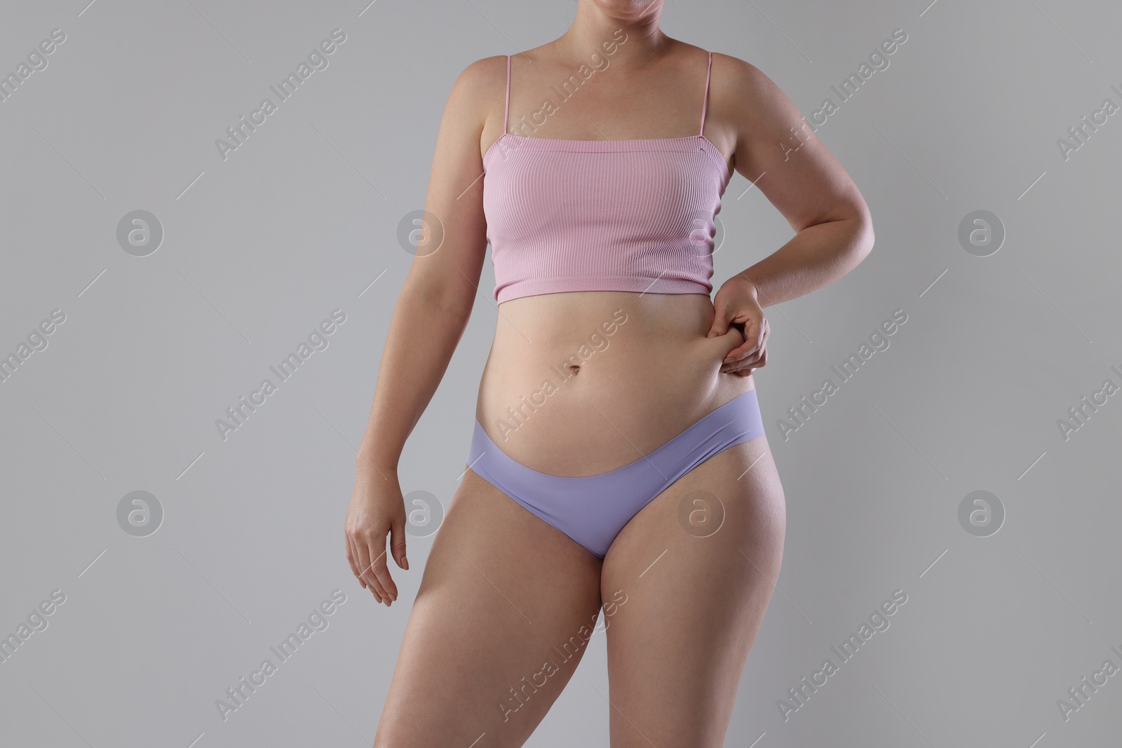 Photo of Liposuction. Woman in underwear touching her belly on grey background, closeup
