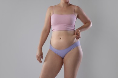 Photo of Liposuction. Woman in underwear touching her belly on grey background, closeup