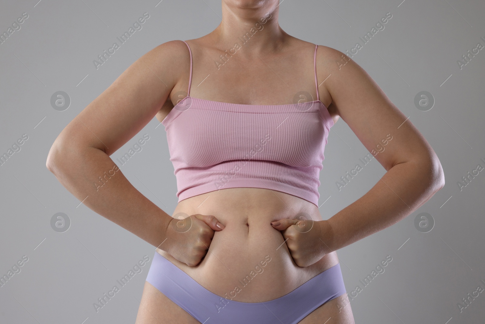 Photo of Liposuction. Woman in underwear touching her belly on grey background, closeup