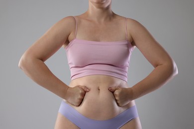 Photo of Liposuction. Woman in underwear touching her belly on grey background, closeup