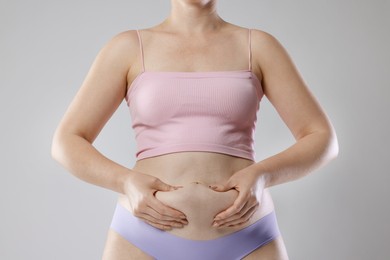 Photo of Liposuction. Woman in underwear touching her belly on grey background, closeup